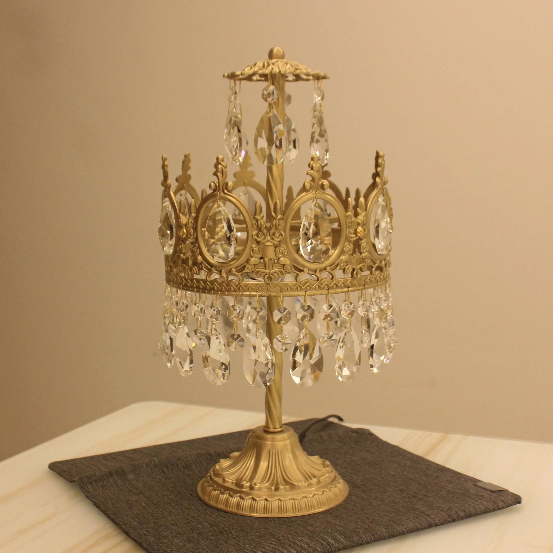 Vintage crystal table lamp with ornate gold base and hanging crystal accents on a table.