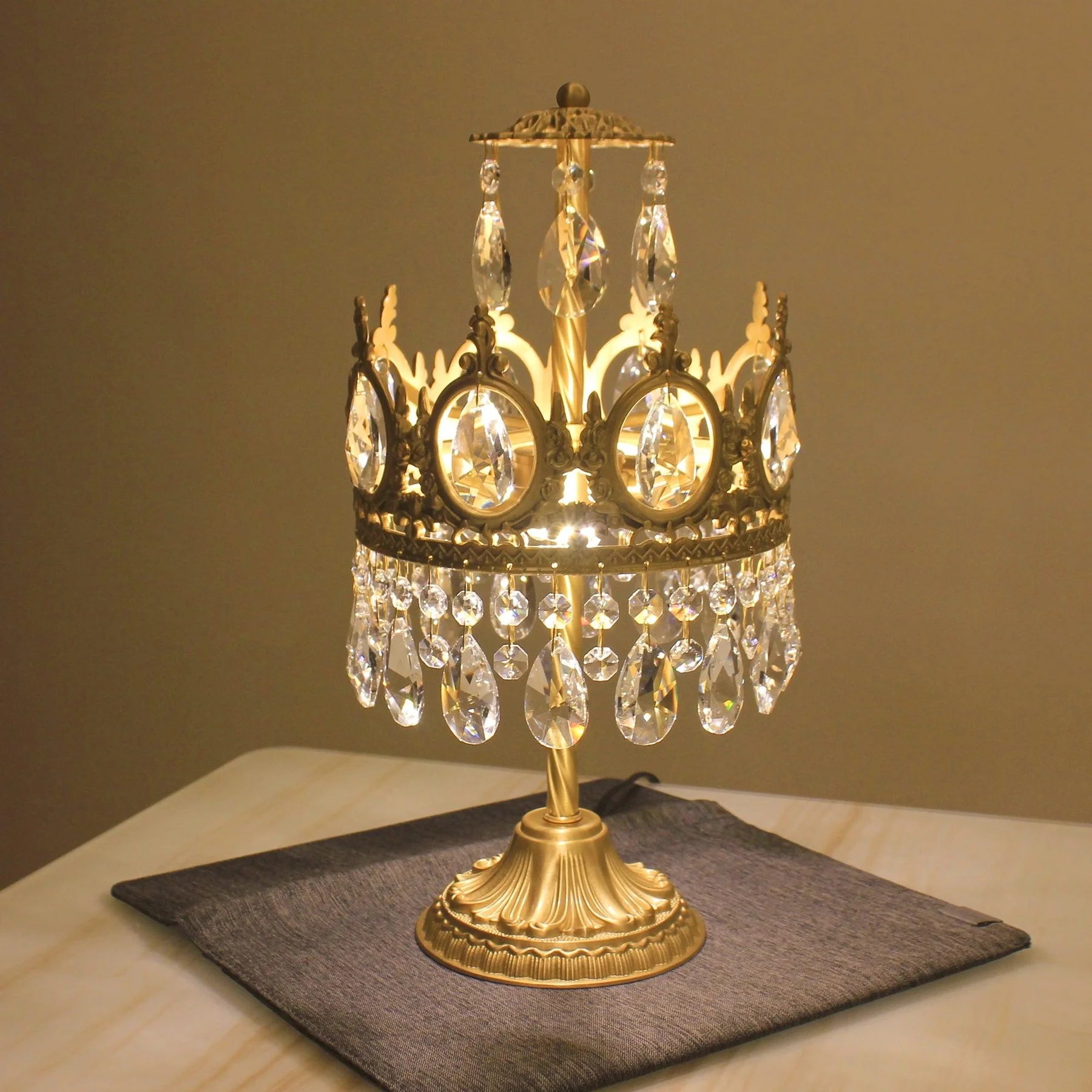 Vintage crystal table lamp with gold base and hanging crystal prisms on marble surface